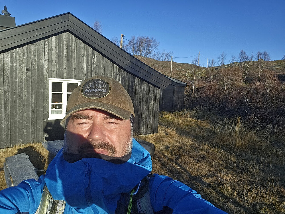 Turstart med vindjakke og ull-lue under caps. Skarp sol rett fram...
