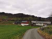 Passerte gårdstunet på fremsiden av løen og over et gjerde til venstre for det grå huset.