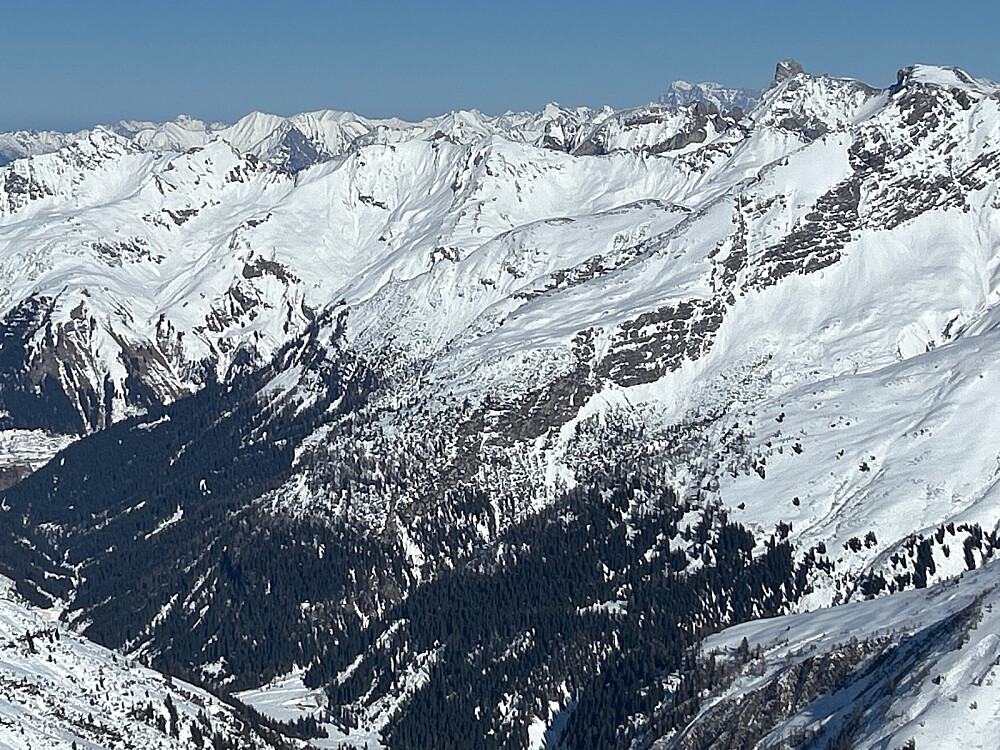 Utsikt fra Valluga og østover hvor Zugspitze i Tyskland ses lengst borte som et litt flatt fjell med snø på toppen.
