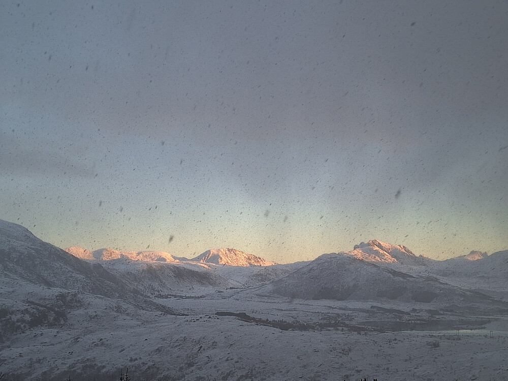 En liten eling med snø mens sola skinner på fjella