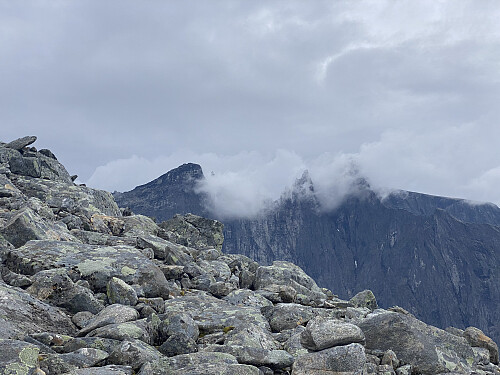 Bilde #5: Utsikt over på Trollveggen, med Trollryggen [1725 m.o.h.] til venstre, mens Brudgommen [1728] og Store Trolltind [1788 m.o.h.] skimtes i skydekket lengre til høyre. Tindenålene imellom er skult av skydekket.