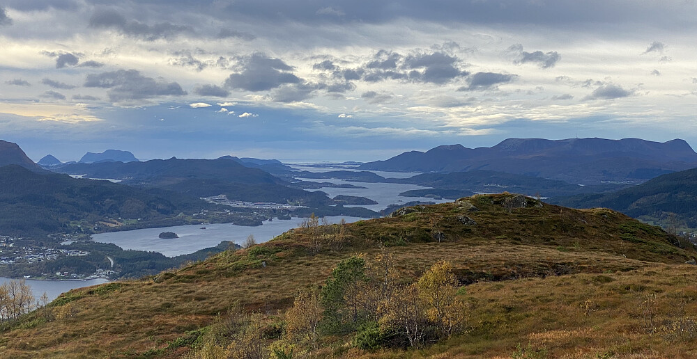 Bilde #9: Utsikt fra toppen, i retning Skodjevika, Ellingsøyfjorden og Grytefjorden. Til venstre i bildet sees Godøya [497] i det fjerne. Til venstre for Godøya igjen, sees Sukkertoppen [314 m.o.h.], og helt ute i billedkanten sees (delvis) Merafta [576 m.o.h.]. Industriområdet like til venstre for Skodjevika er Digerneset.