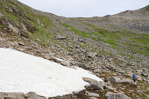 Terrain in the corrie on approach to the summit ridge: snow patch and boulder field.