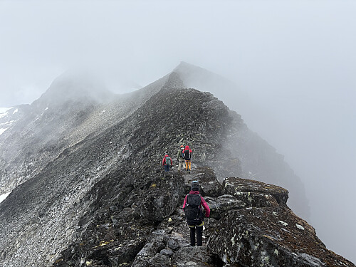 Snart oppe på Austre Stølsnostinden midt i bildet. Midtre Stølsnostind ses i tåka bak til venstre