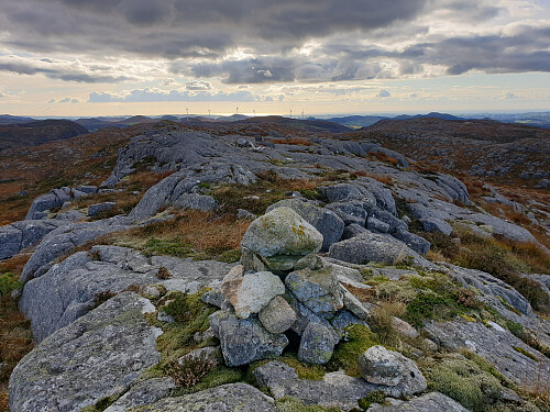 Liten varde og nedfalt signalkors/ trigpunkt. Ser Vardafjell 384 med havet bak.