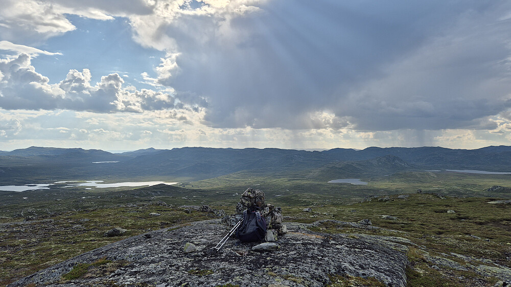 På toppen av Nordre Olabunut (1252). Utsikt rett mot vest. Vannet nedenfor til venstre er Våervatn. Bygeskyene bak til høyre er de som på starten av turen hadde virket litt truende, men som heldigvis dro vest for meg. Disse bygene hadde også gitt fra seg noen lyn.
