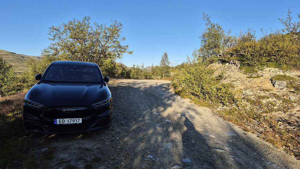 Parkering langs veien rett før den stengte bommen, som kan skimtes gjennom buskene bitte litt til høyre i bildet.