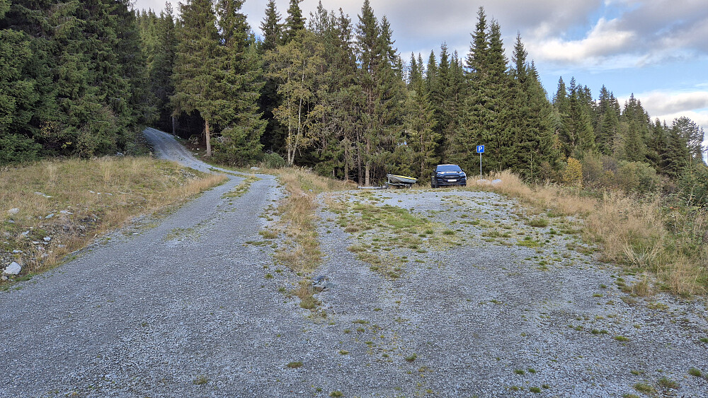 Satte igjen bilen på en ganske stor, merket parkeringsplass. Veien opp til Listul forsvinner inn i skogen til venstre.