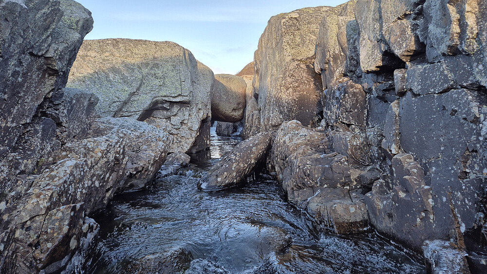Steinhoppet. En temmelig rund kampestein har kilt seg fast og henger over elva Mår, og fungerer som bru der stien går. 