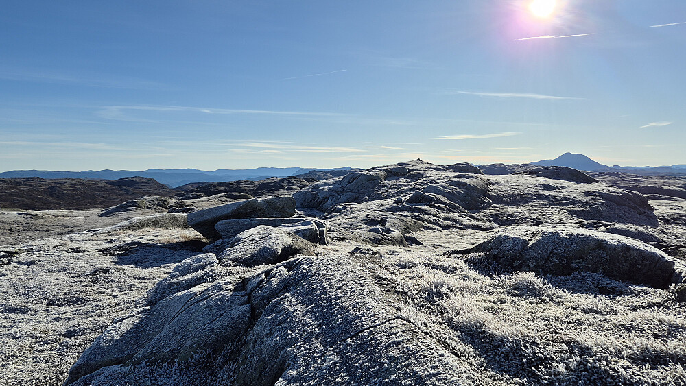 Jeg står på høyden ca 130 meter nordvest for selve toppen av Staupsfjellet (1340), som her ses litt til høyre i bildet med en svart, liten varde på toppen. Gaustatoppen (1883) hever seg høyt over landskapet lengre bak til høyre. 