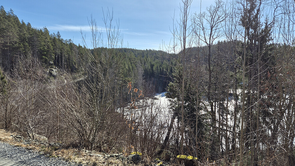 Jeg står på Slåttavegen og har det islagte Kjennkåstjenn nedenfor til høyre. Her skal jeg straks forlate veien og gå opp mot Åslandheia (215). Den slake åsen i bakgrunnen midt i bildet er en del av Storefjell (266).